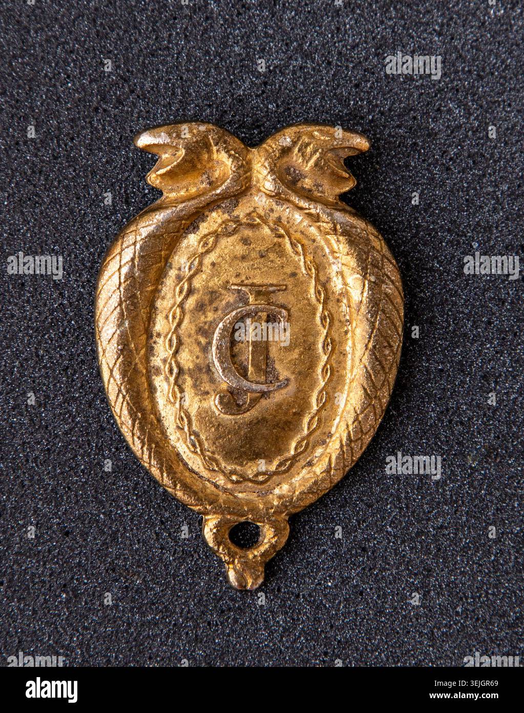 Antico distintivo giudiziario austro-ungarico con monogramma JC e serpenti caduceo, stemma delle forze dell'ordine in ottone vintage o ufficiale della giustizia. Vecchio segno d'oro Foto Stock