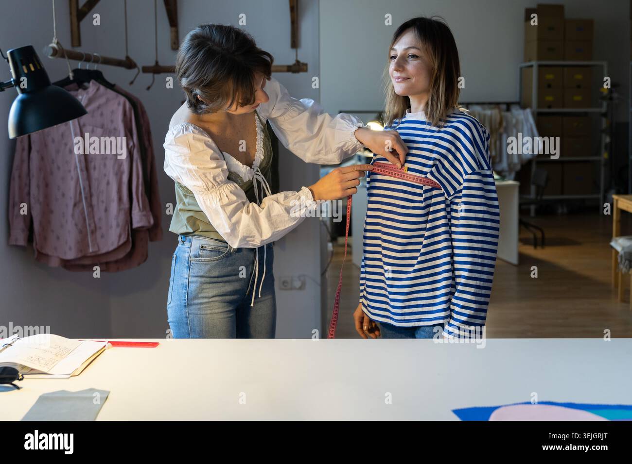 La donna stilista di moda prende le misure con nastro di misurazione del cliente prima di personalizzare i vestiti Foto Stock