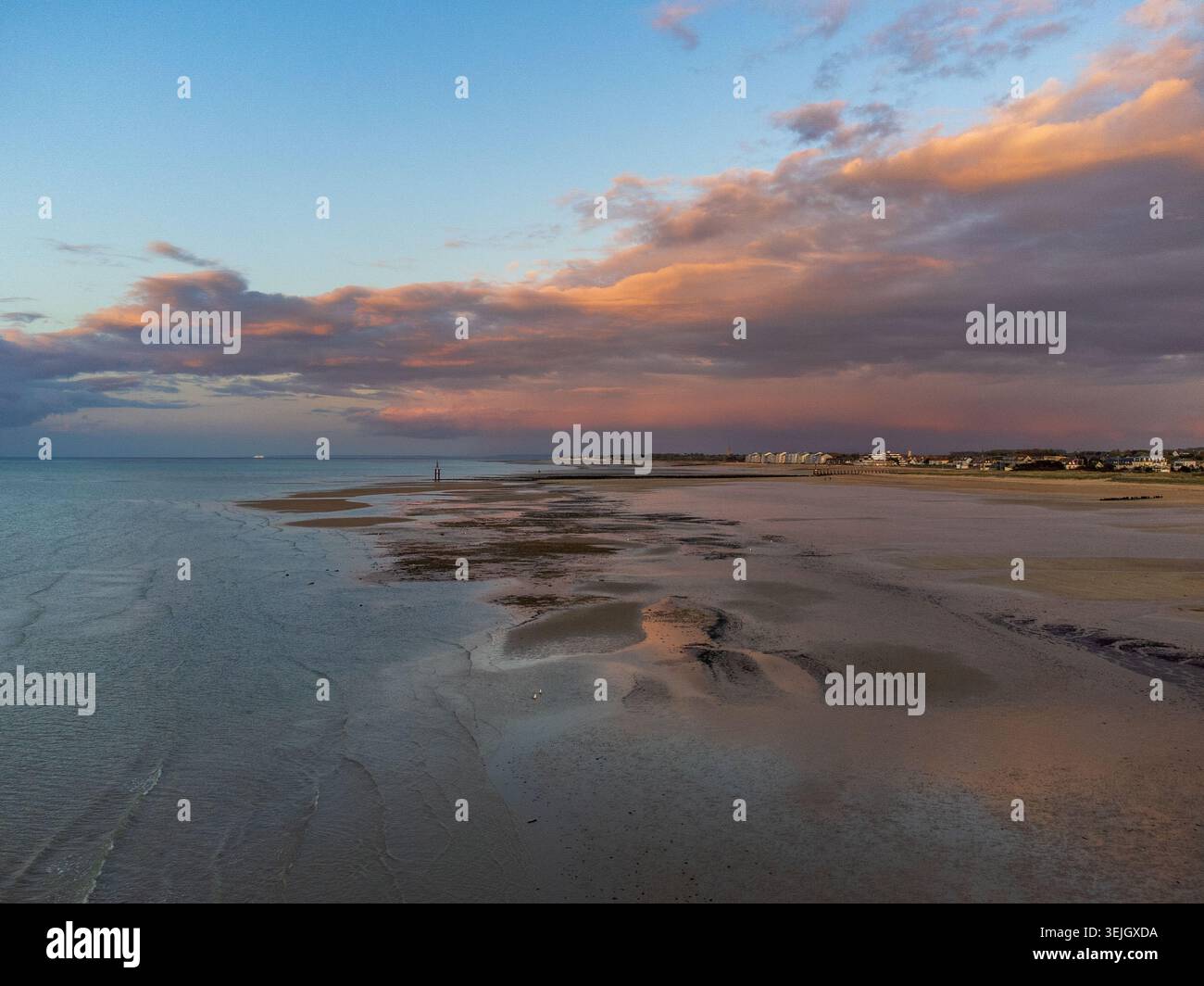 Spettacolare vista aerea di Courseulles-sur-Mer con bassa marea che rivela banchi di sabbia e piscine riflettenti. Sullo sfondo, la città costiera e una bellezza Foto Stock