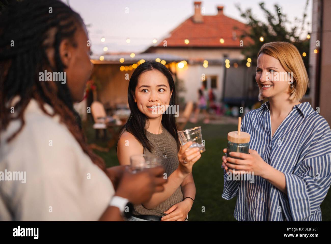 Diverse donne e amiche che si divertono con una festa in giardino con un drink Foto Stock