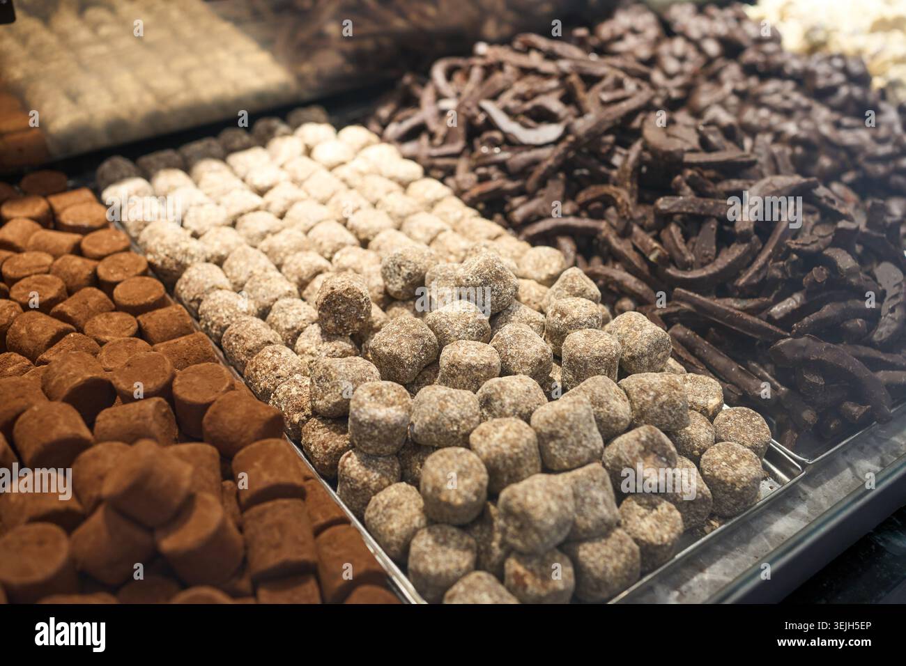 Varie tartufi al cioccolato fatti a mano, pralines e dolci esposti sugli scaffali di una vetrina di pasticceria Foto Stock