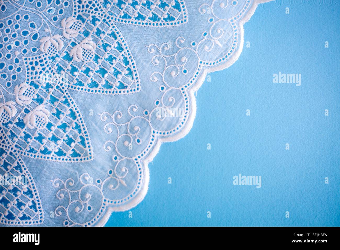 Motivo in pizzo, dettaglio di una tovaglia isolata su sfondo blu. Confine artistico. Artigianato, vintage. Concetto di hobby. Vista dall'alto. Foto Stock