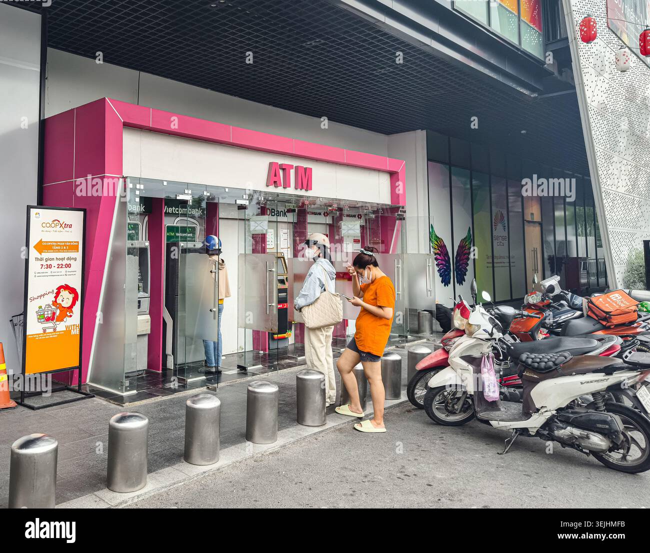 I clienti sono in fila per utilizzare le macchine ATM all'interno di un contenitore rosa brillante, ho chi Minh City, Vietnam, Asia Foto Stock