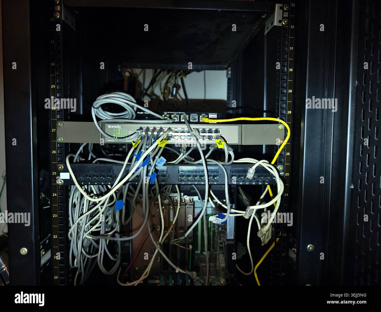 Switch di rete per rack server disorganizzati e patch panel, numerosi cavi Ethernet collegati ai dispositivi, che mostrano un'elevata densità di connessioni. Foto Stock