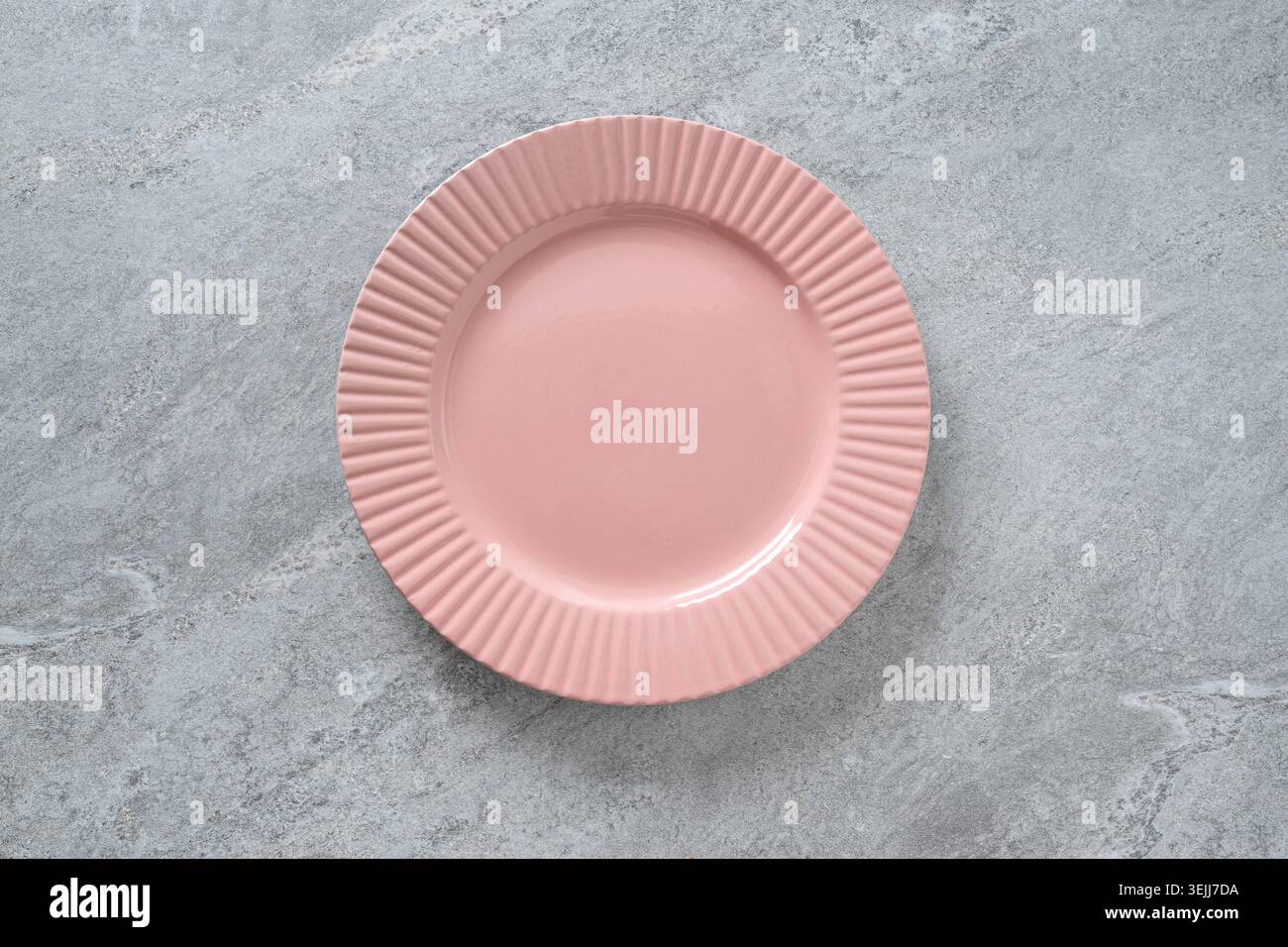 Piastra in ceramica rosa vuota sulla superficie in pietra grigia. Mockup minimo per la preparazione del tavolo per la presentazione dei piatti, il design dei menu, i blog delle ricette e il branding dei ristoranti. Foto Stock