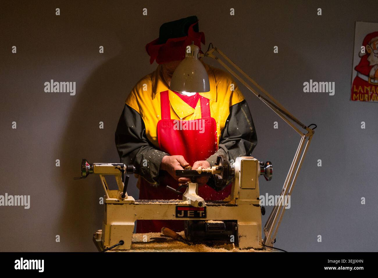 Montepulciano, Italia - 01 gennaio 2023: Falegname intagliando legno su tornio sotto lampada in officina Foto Stock