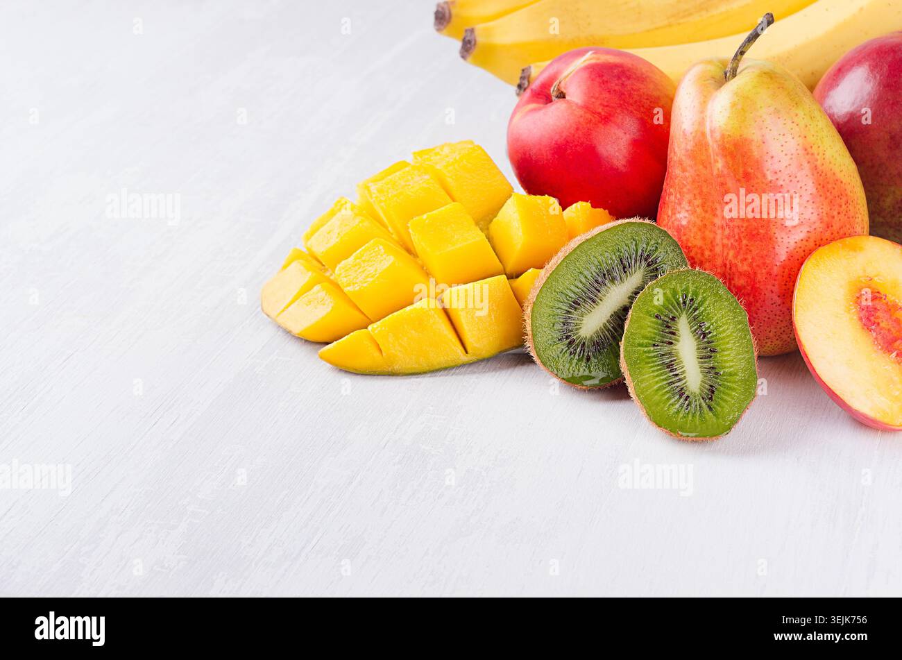 Mix di frutta colorata - frutta intera e succose fette a fette - mango, banana, pera, pesca, kiwi, primo piano di nactarina su bianco morbido con Foto Stock