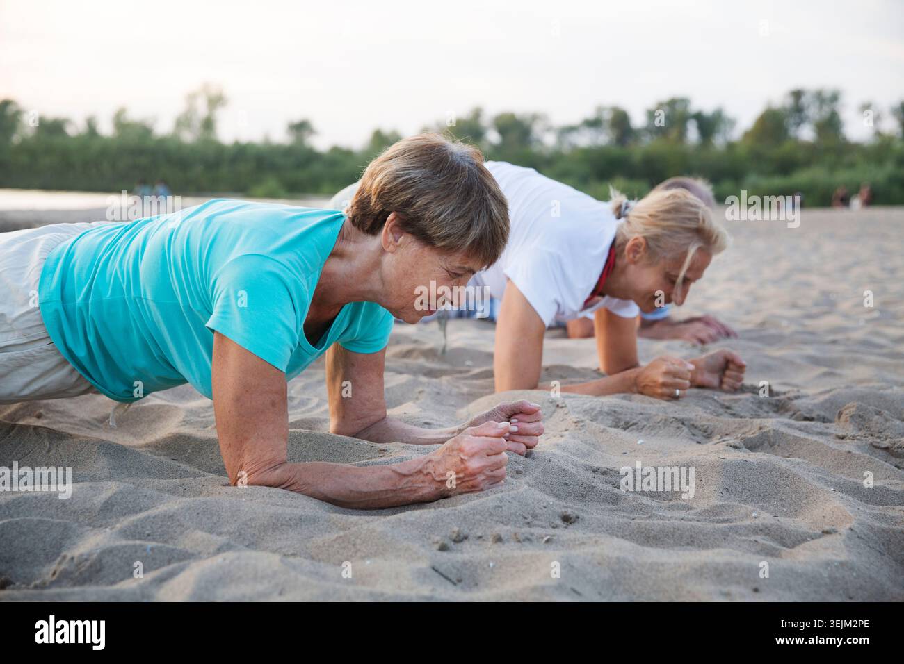 Gruppo di persone anziane fanno esercizio fisico al tramonto sulla spiaggia. Stile di vita sano Foto Stock