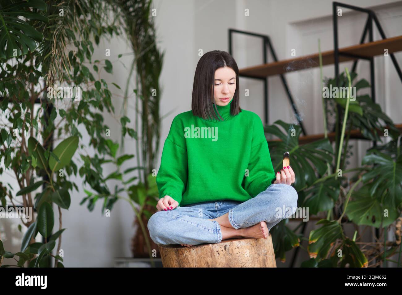 Il bastoncino palo santo è sinonimo di relax, sollievo dallo stress e affaticamento. aromaterapia a casa. donna con palo santo in mano per ener Foto Stock