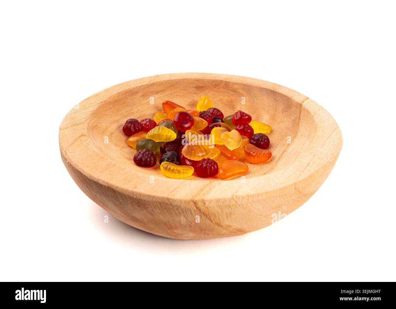 Pile di caramelle gommose di frutta in una ciotola di legno isolata, pillole vegane di marmellata da masticare, mucche di gelatina colorate su sfondo bianco Foto Stock