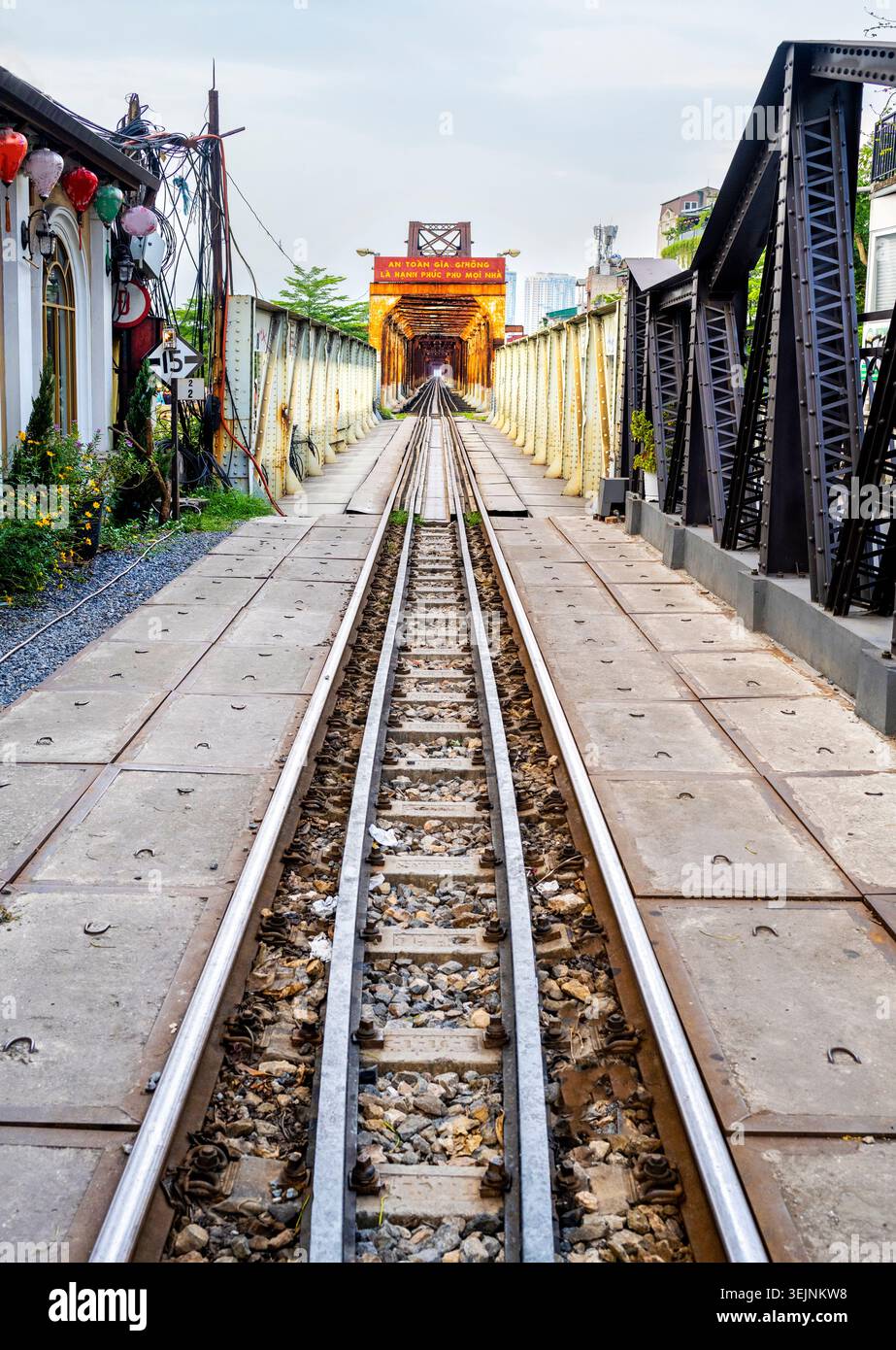 Nel quartiere vecchio della città nel Vietnam del Nord, un unico binario ferroviario conduce attraverso il vecchio ponte in acciaio coloniale francese, che attraversa la R di Hanoi Foto Stock