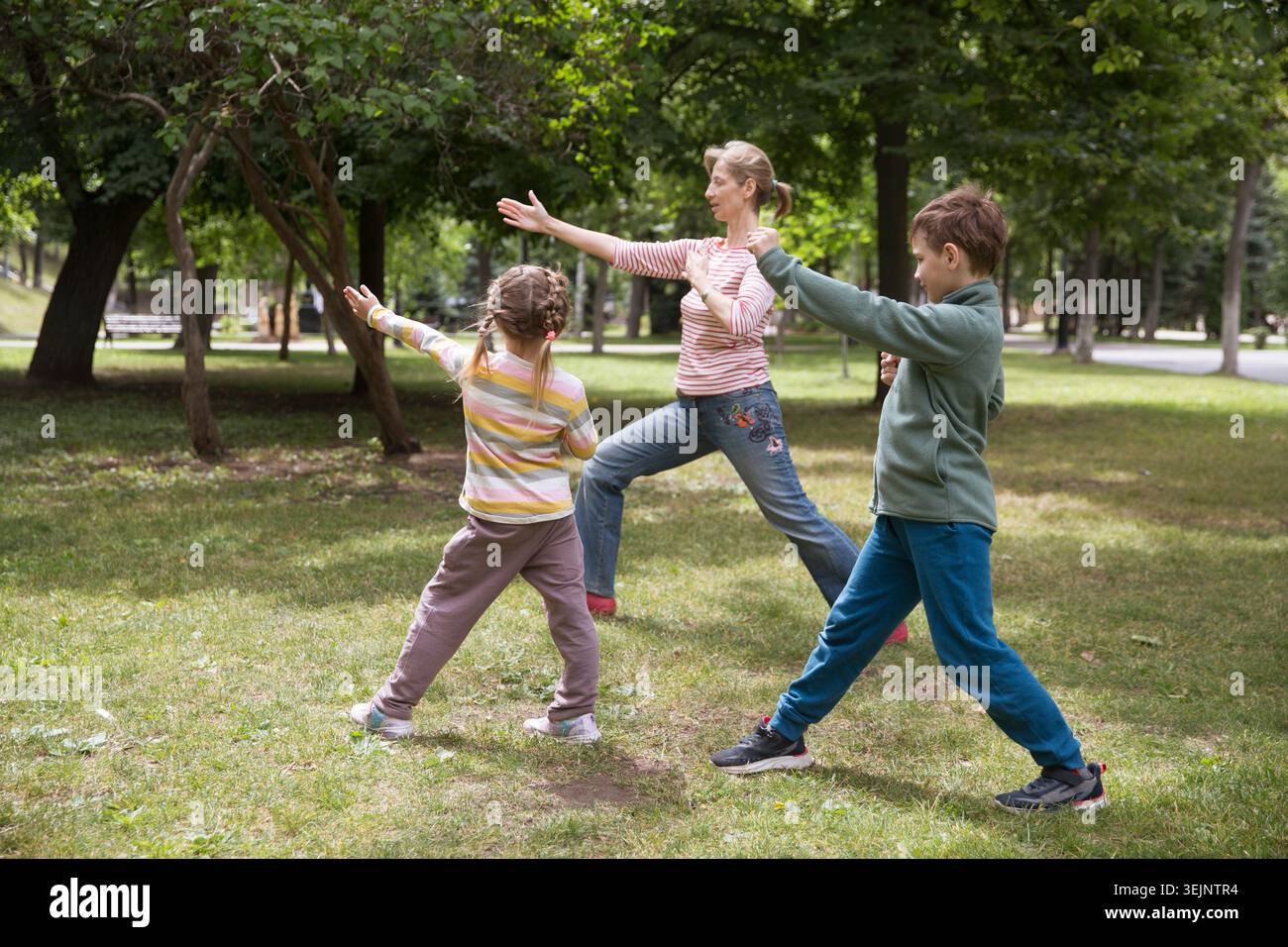 Mamma e due bambini in famiglia praticano Tai chi Chuan in un parco. Capacità di gestione cinese QIS energia. Foto Stock