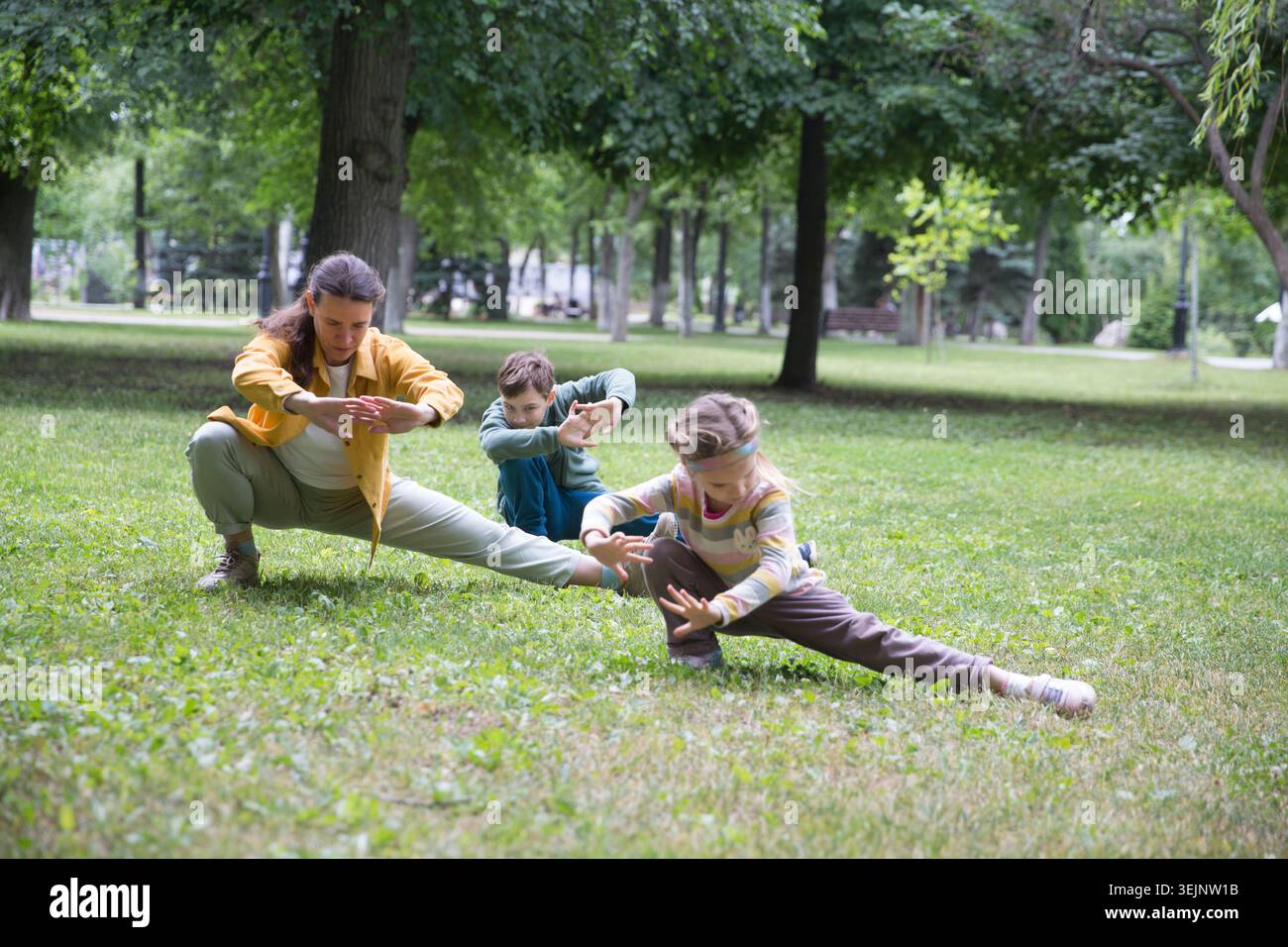 Mamma e due bambini in famiglia praticano Tai chi Chuan in un parco. Capacità di gestione cinese QIS energia. Foto Stock