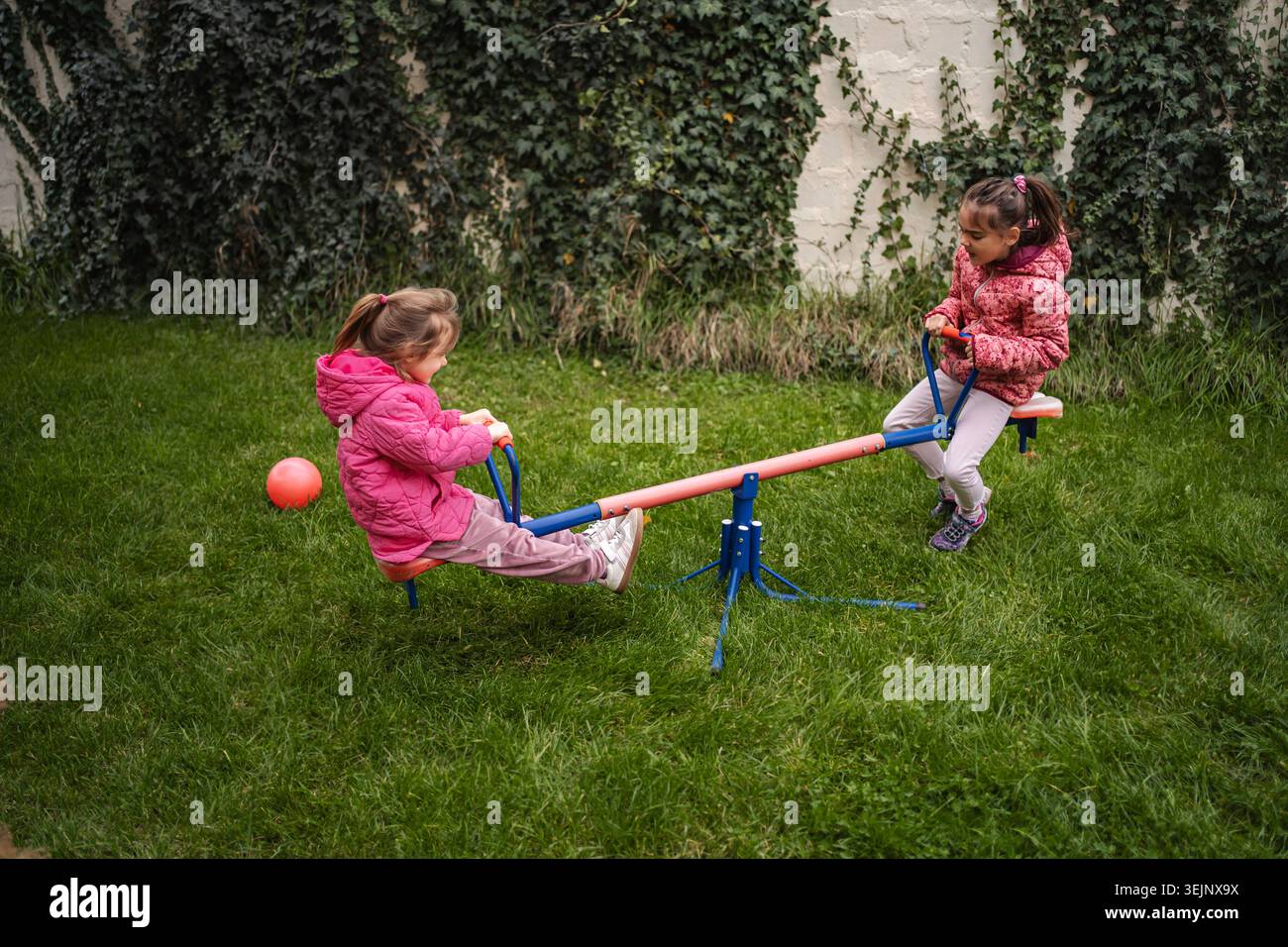 Ragazze che giocano all'aperto su alghe marine nel cortile di erba verde Foto Stock