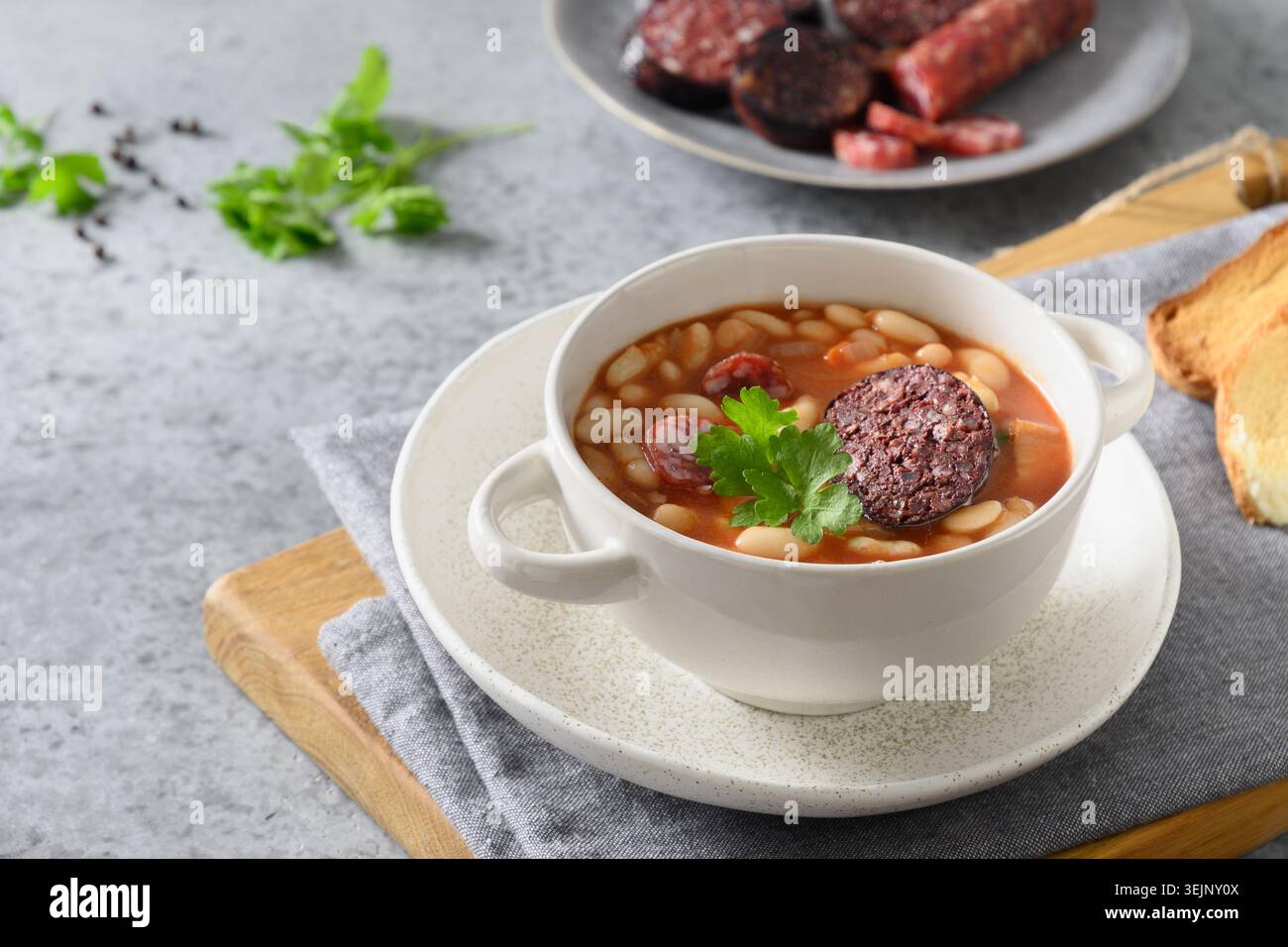 Stufato di fabada spagnola con salsiccia di sangue su un tavolo grigio. Foto Stock