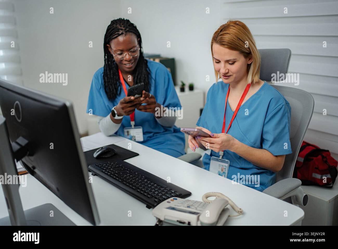 Operatori sanitari distratti dagli smartphone durante il turno di lavoro Foto Stock