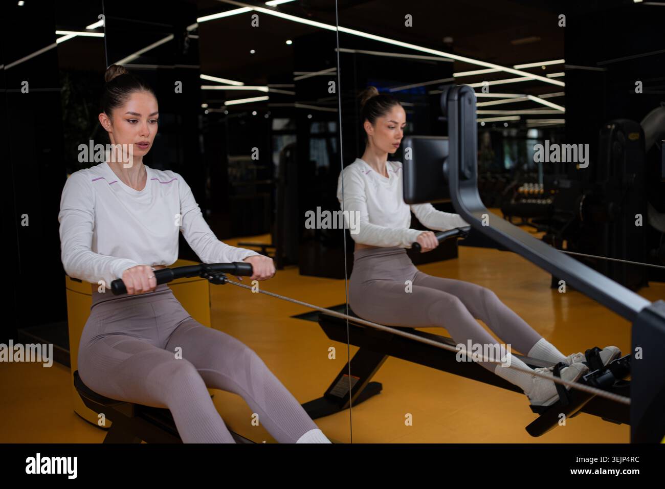Donna che si allena con una macchina per remare in palestra Foto Stock