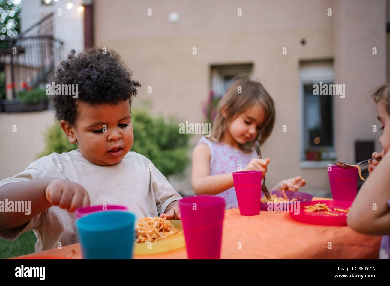 I bambini si godono la pasta durante la festa di compleanno all'aperto Foto Stock