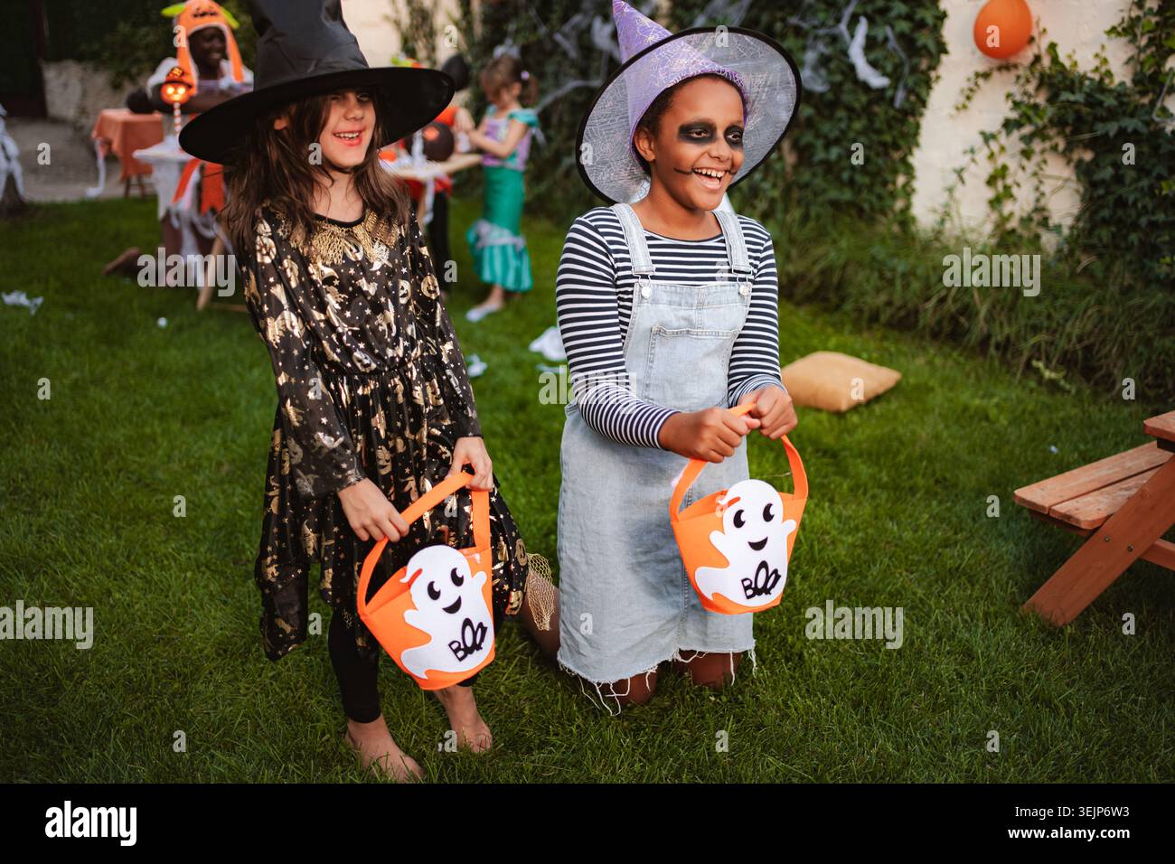 Due ragazze allegre che indossano costumi di Halloween tenendo i secchi per scherzare Foto Stock