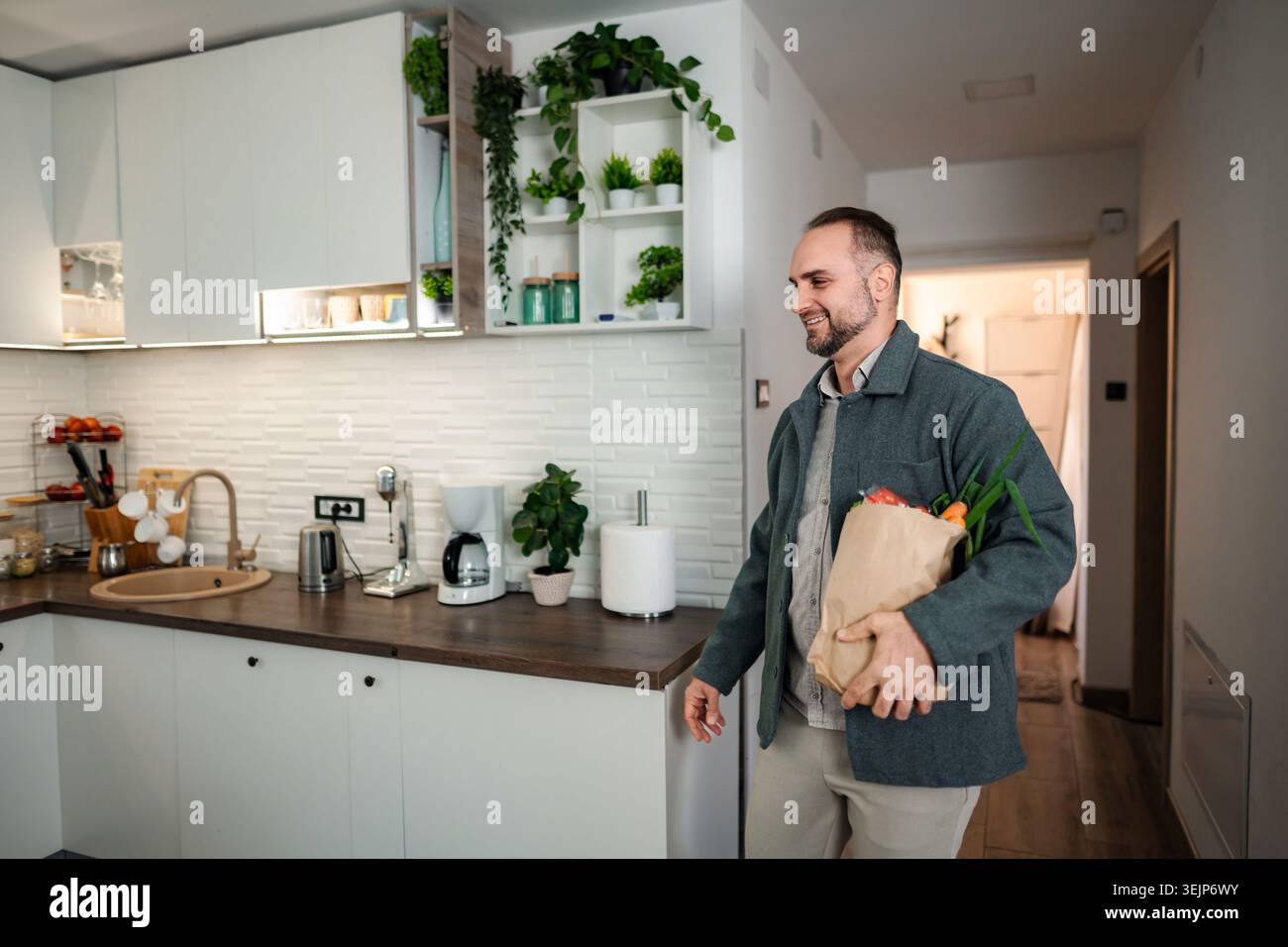 Uomo che torna a casa con un sacco di carta in cucina Foto Stock