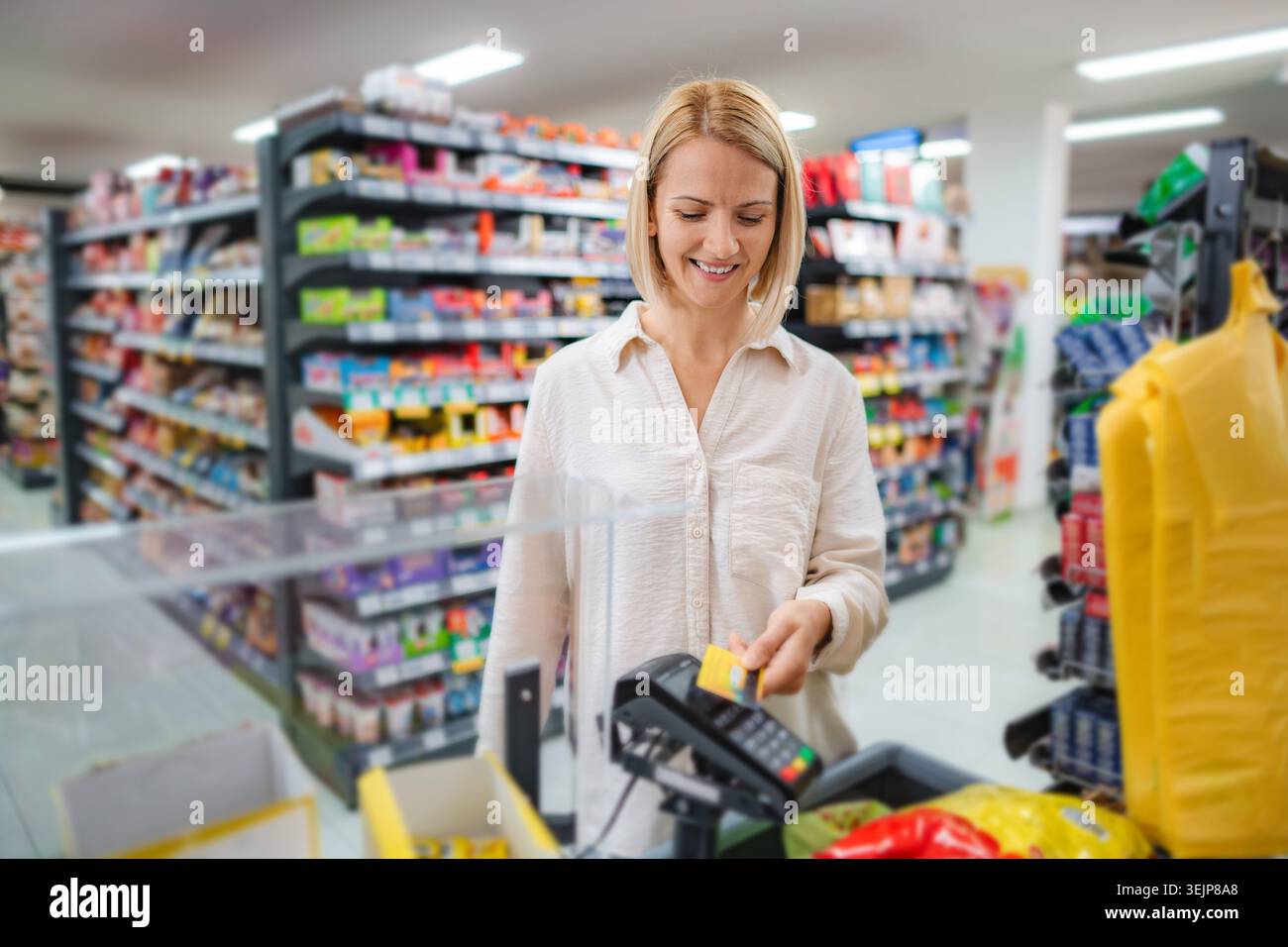 Donna che paga per la spesa usando un terminale senza contatto per carte di credito Foto Stock