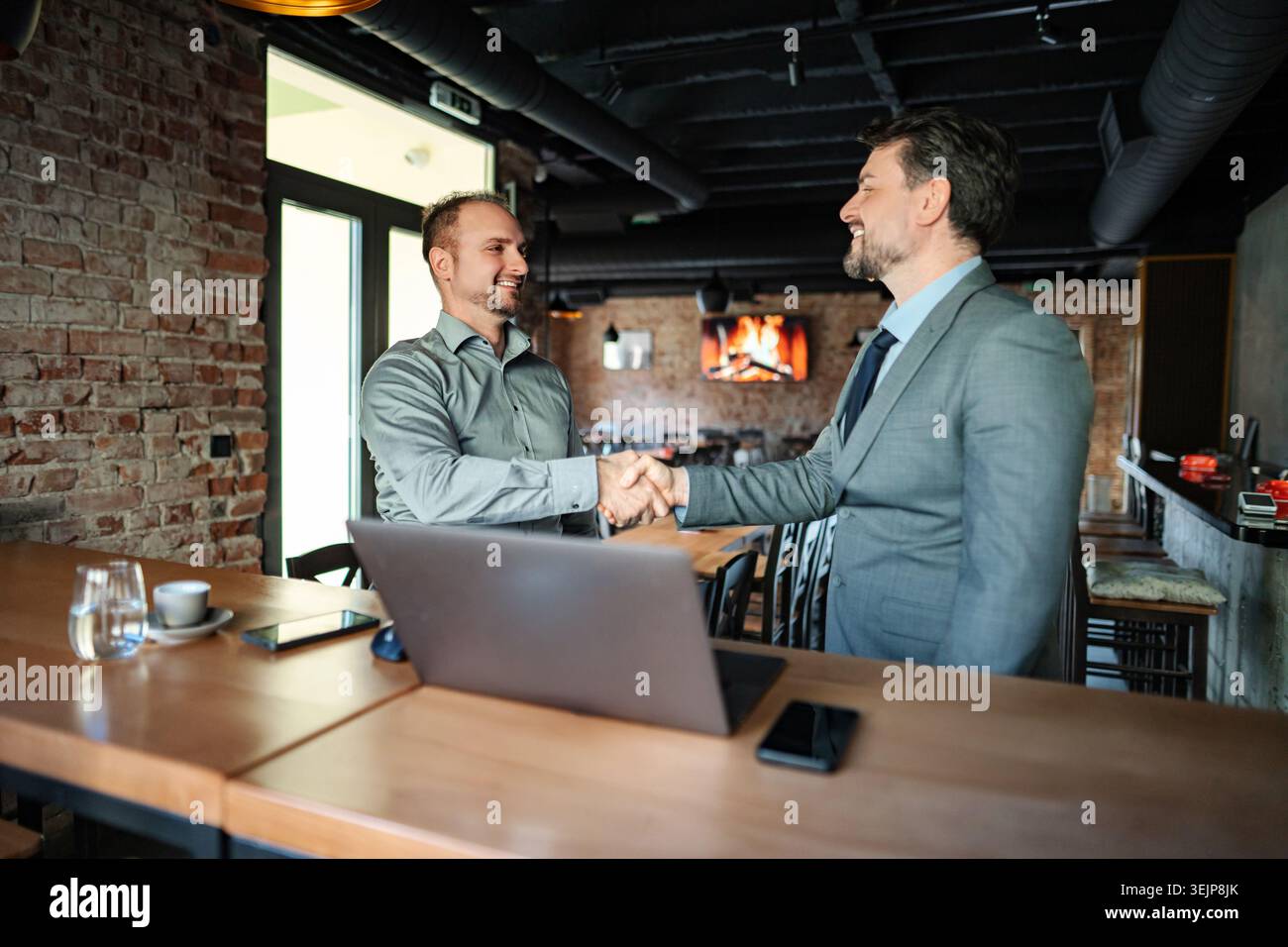 Uomini d'affari che stringono la mano facendo un accordo di partnership in un bar Foto Stock