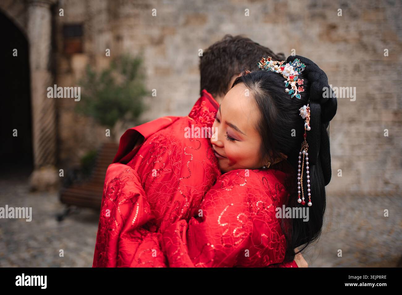 Coppie di nozze interrazziali che abbracciano un abbigliamento tradizionale Foto Stock