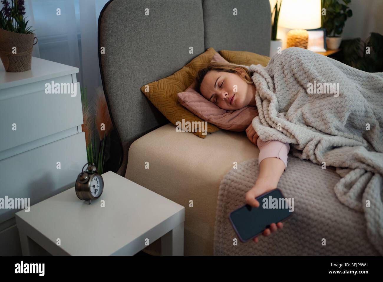 Donna che dorme nel letto con smartphone in camera da letto Foto Stock