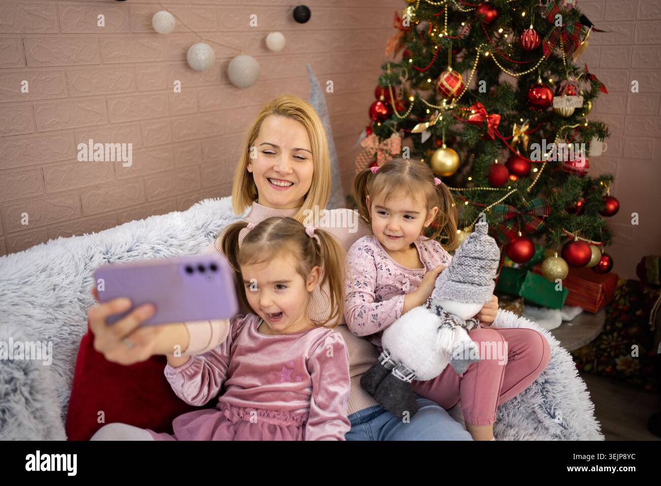 Madre e figlie si fanno selfie sull'albero di natale Foto Stock