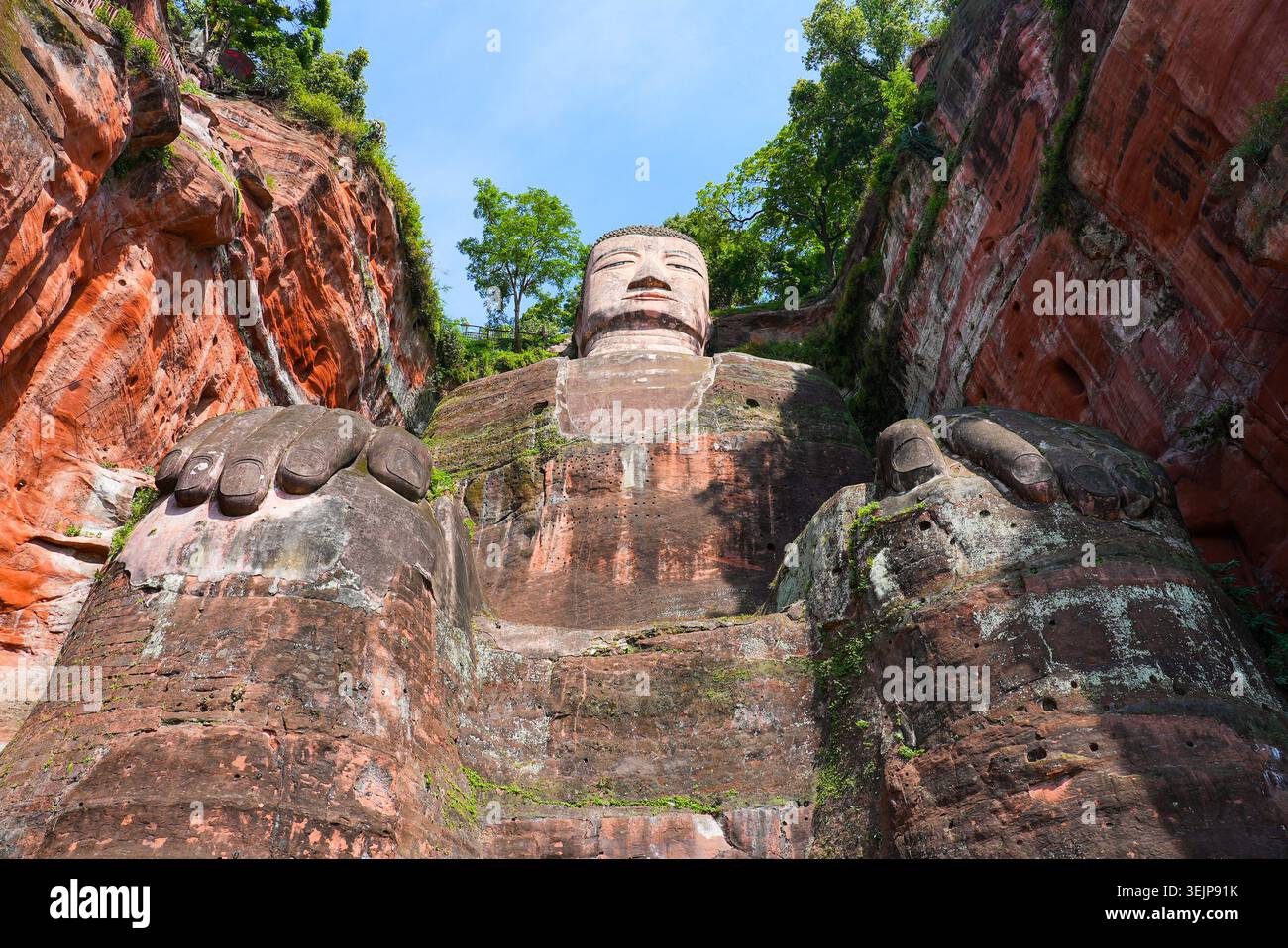 Vista ad angolo basso del maestoso Buddha gigante di Leshan seduto scolpito nella parete della scogliera di arenaria a Sichuan, Cina Foto Stock