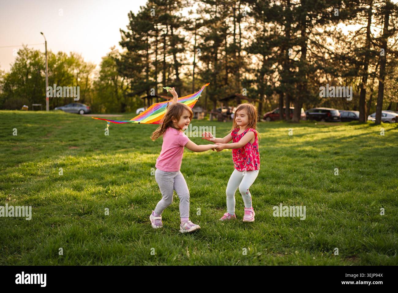 Momenti di gioia condivisi da due ragazze che giocano con un aquilone colorato Foto Stock