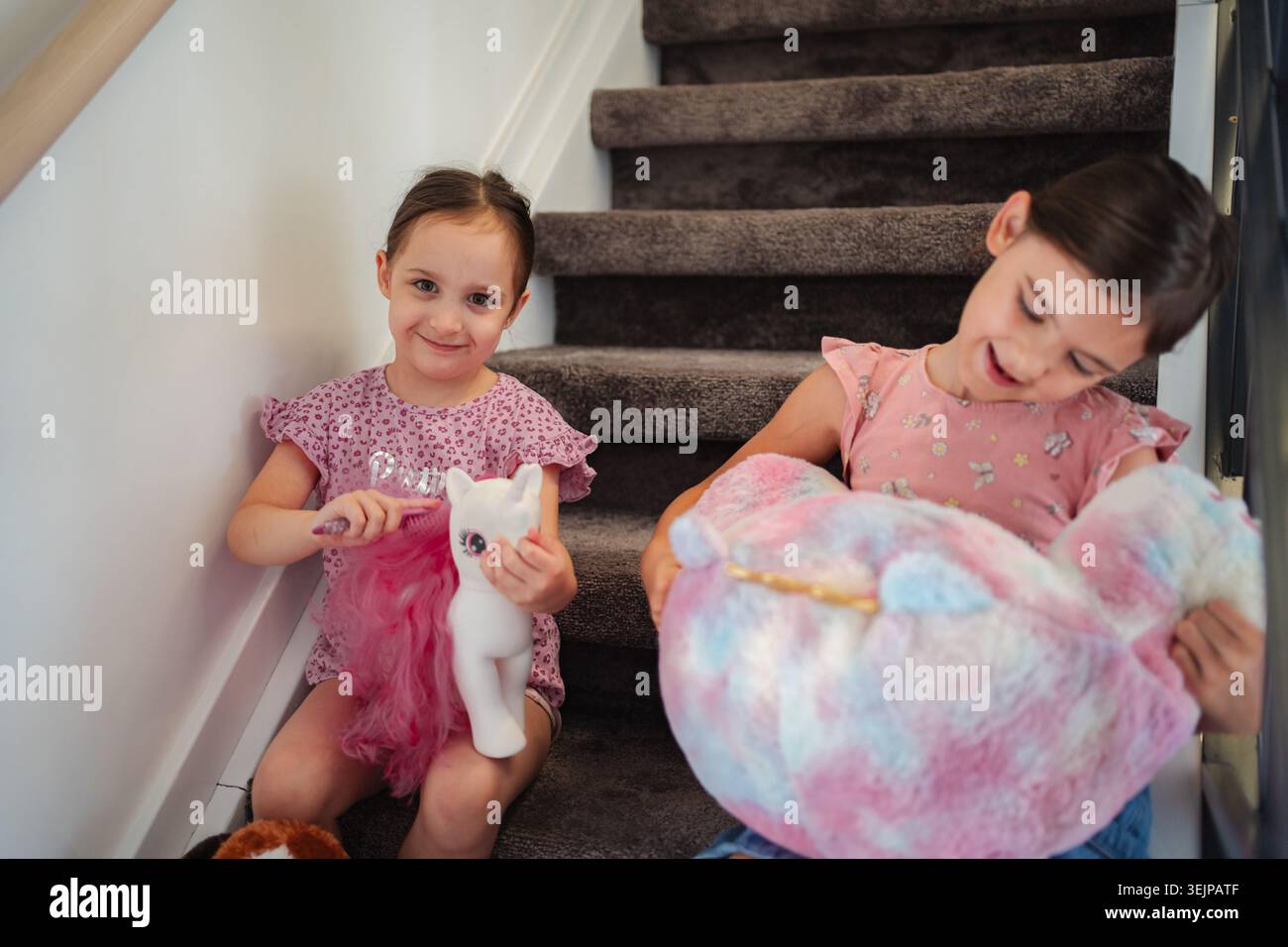 Due sorelle che giocano con i loro unicorno sulle scale Foto Stock