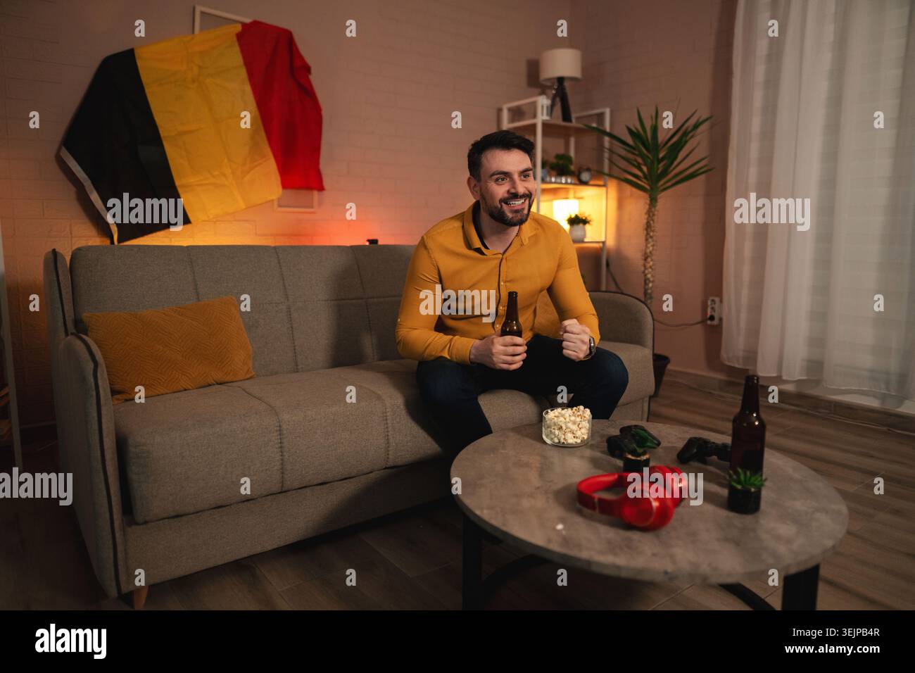 L'emozione riempie la stanza mentre gli appassionati di sport si godono una serata accogliente a casa festeggiando una partita con spuntini e bevande Foto Stock