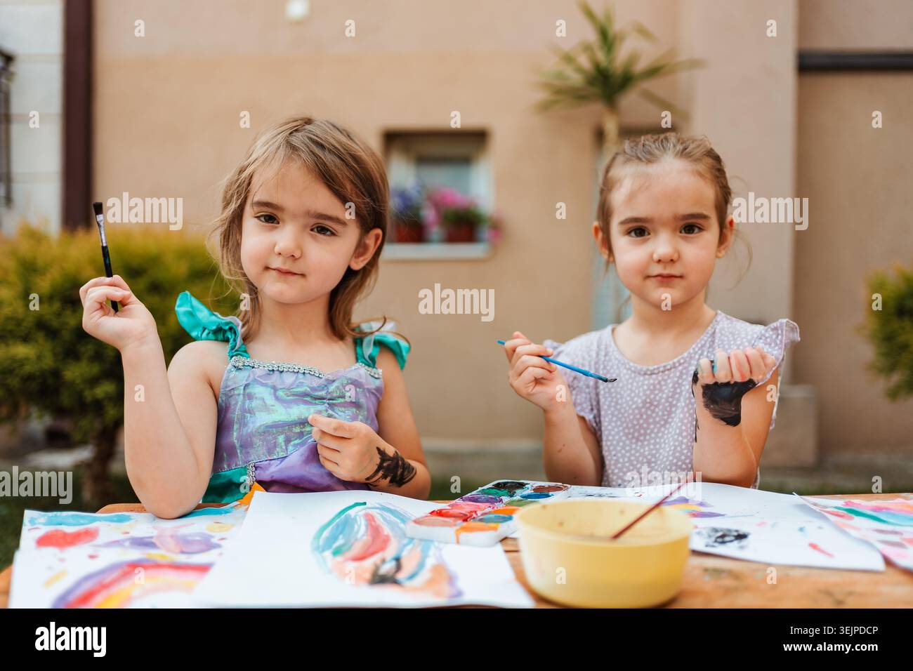Due ragazze in età prescolare che dipingono con acquerelli nel cortile posteriore Foto Stock