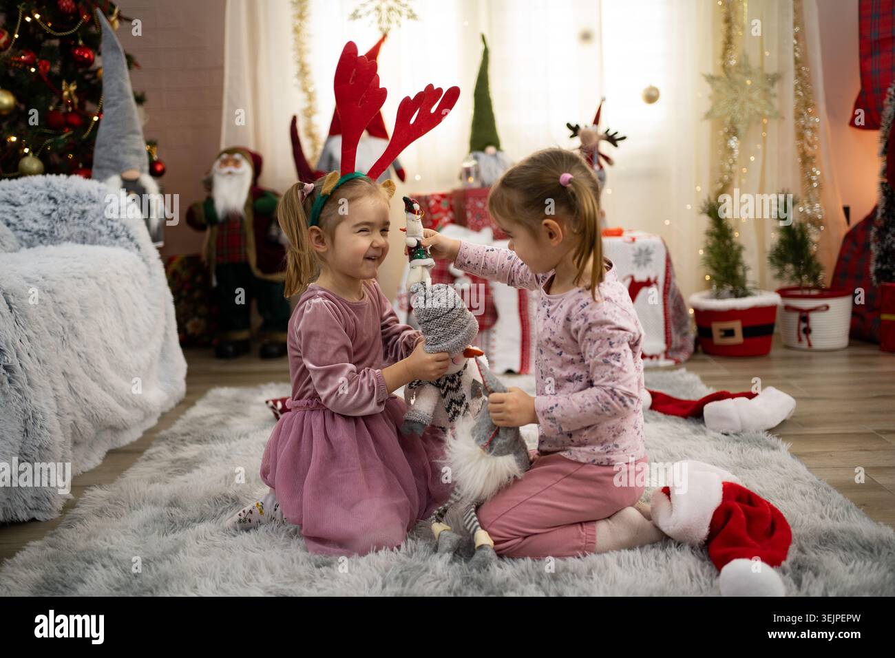 Due sorelle si divertono il giorno di natale, giocando con un giocattolo imbottito Foto Stock