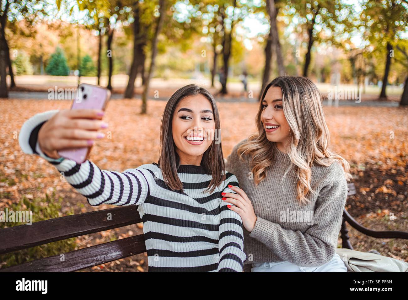 Due ragazze che condividono risate e amore durante una splendida giornata autunnale nel parco Foto Stock