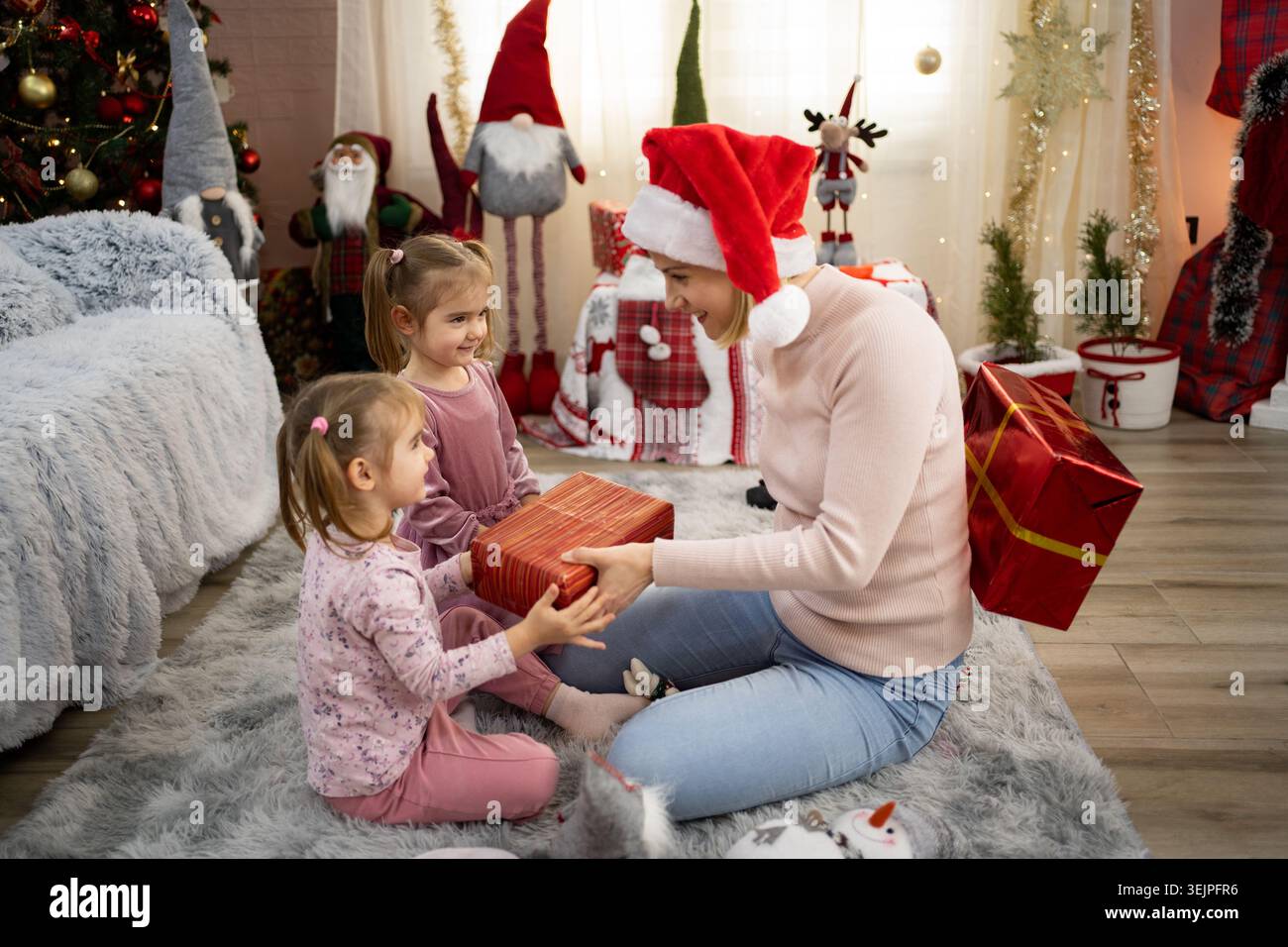 Madre che dà regali di Natale alle sue due figlie Foto Stock