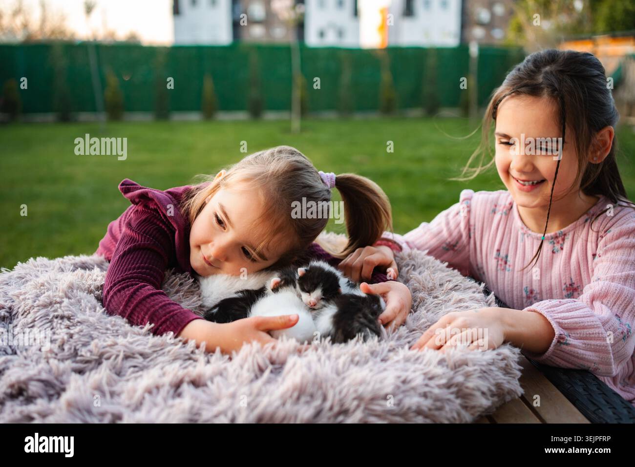 Ragazze che vivono la gioia di accarezzare i gattini appena nati nel cortile Foto Stock
