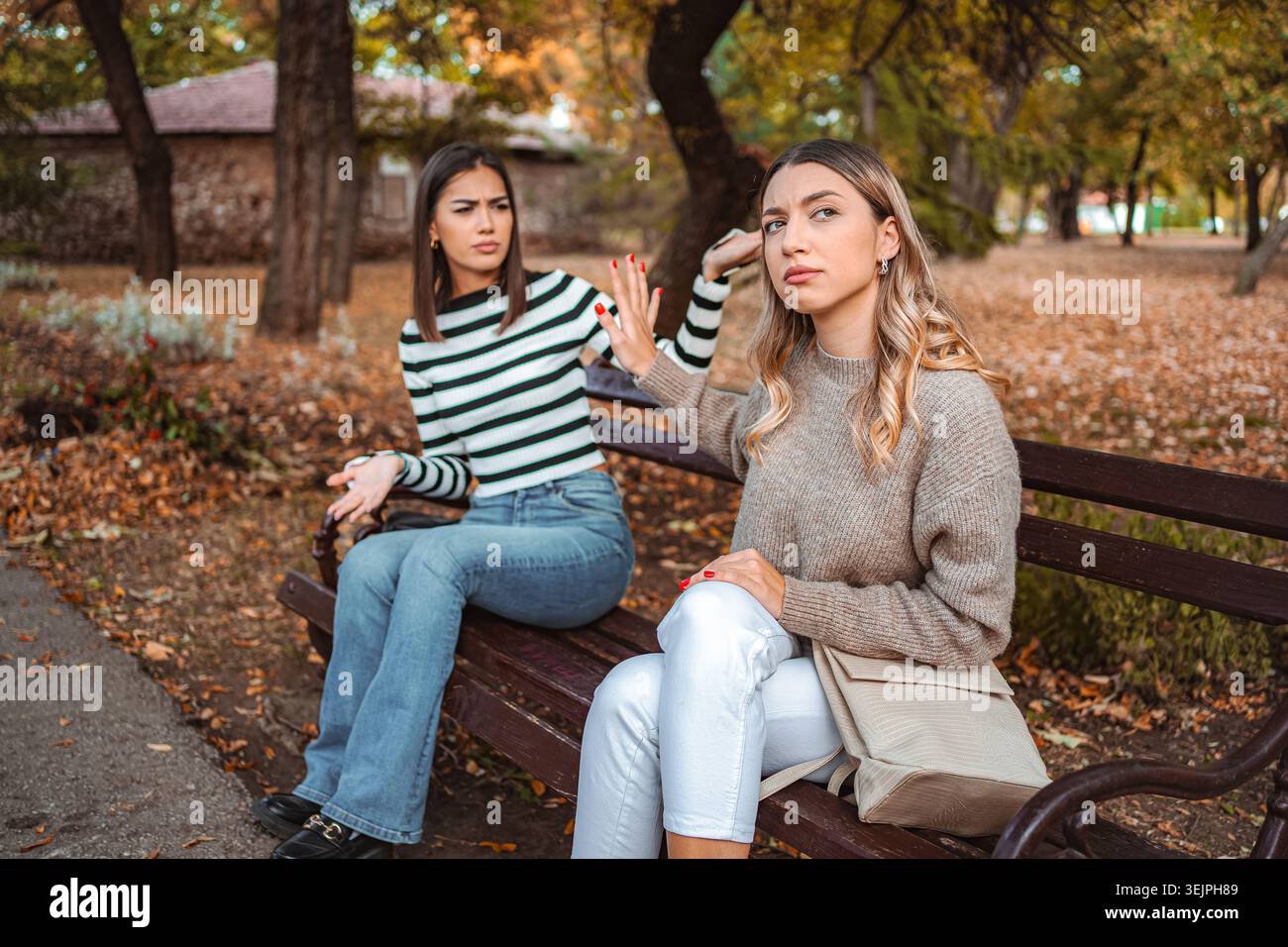 Due ragazze che condividono un momento autunnale in un tranquillo parco Foto Stock