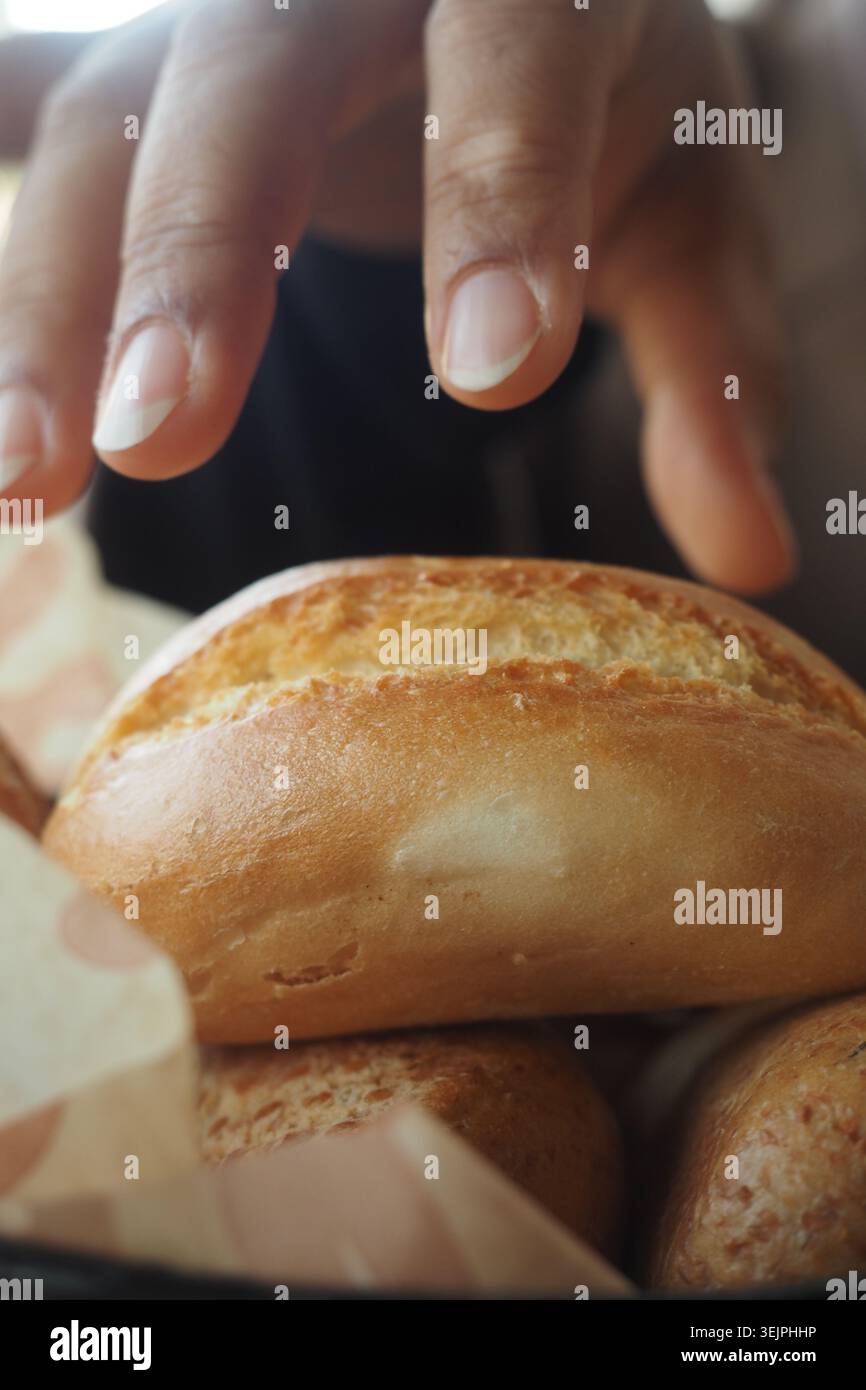 La persona cerca un panino in un cestino Foto Stock