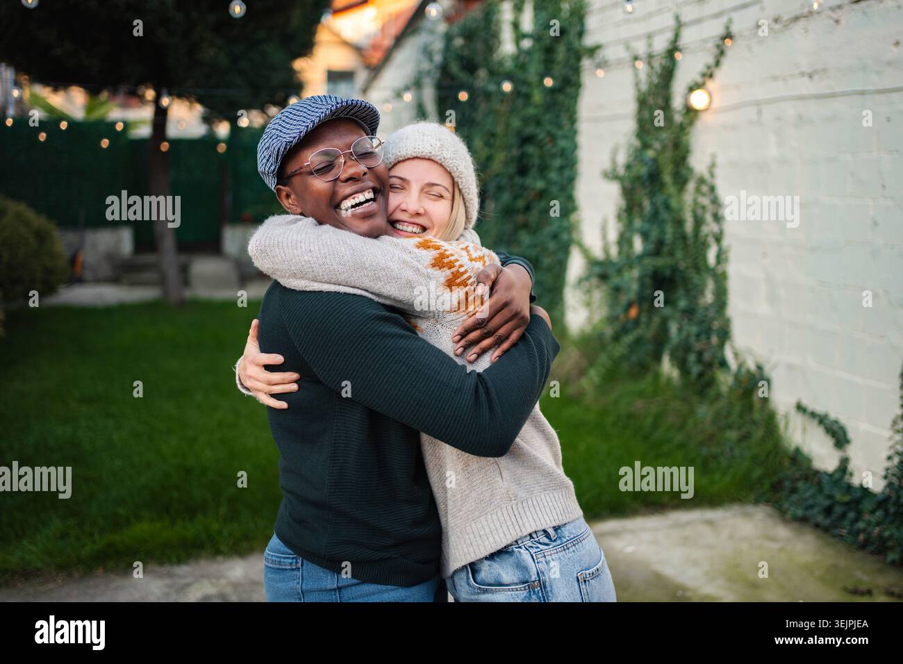 Felice coppia di giovani adulti multietnici che abbraccia e sorride all'aperto Foto Stock