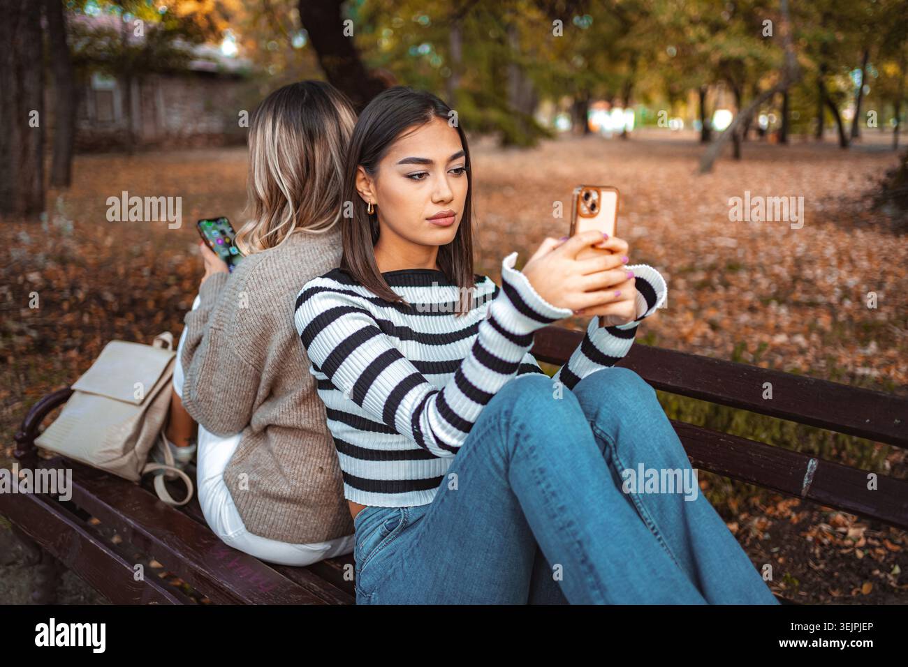 Le ragazze si divertono a vivere momenti autunnali mentre condividono esperienze sul telefono insieme Foto Stock