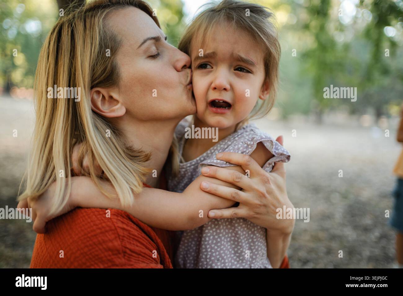 Madre conforta la figlia che piange al parco Foto Stock