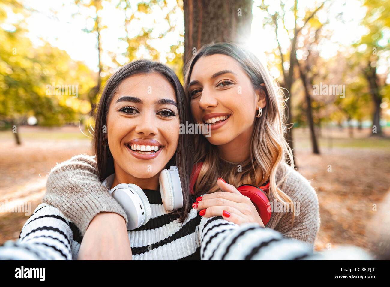 Momenti autunnali felici condivisi da due amici in un parco illuminato dal sole Foto Stock