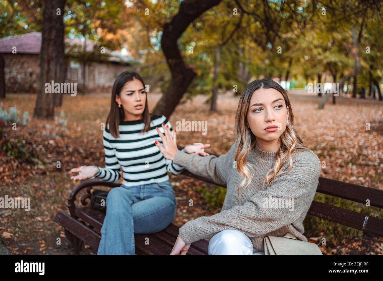 Due ragazze condividono un momento autunnale di disaccordo in un parco Foto Stock