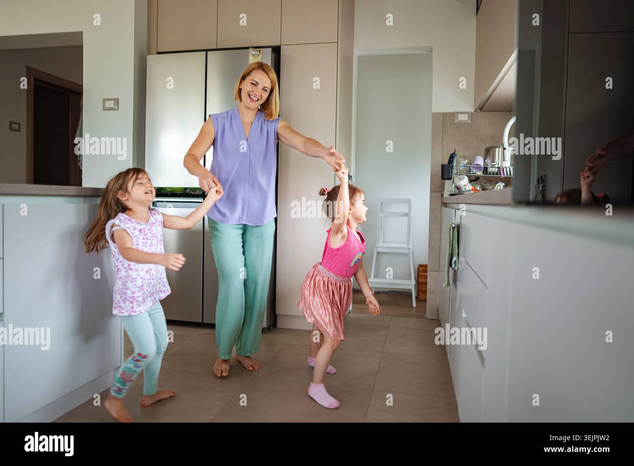 Momenti felici di bambini che ballano in una cucina accogliente Foto Stock