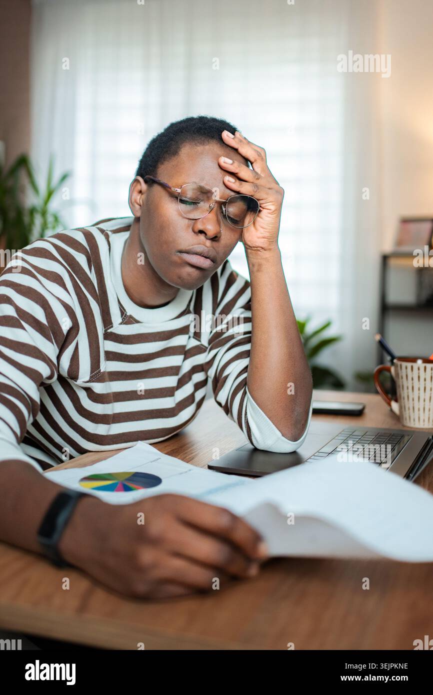 Giovane donna adulta che soffre di stress e mal di testa durante il lavoro da casa Foto Stock
