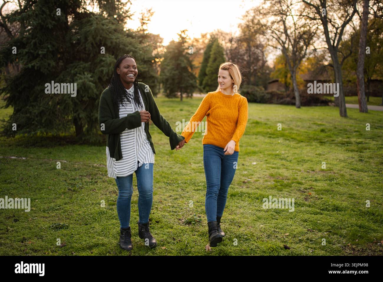 Diverse donne e amici camminano mano nella mano all'aperto ridendo Foto Stock
