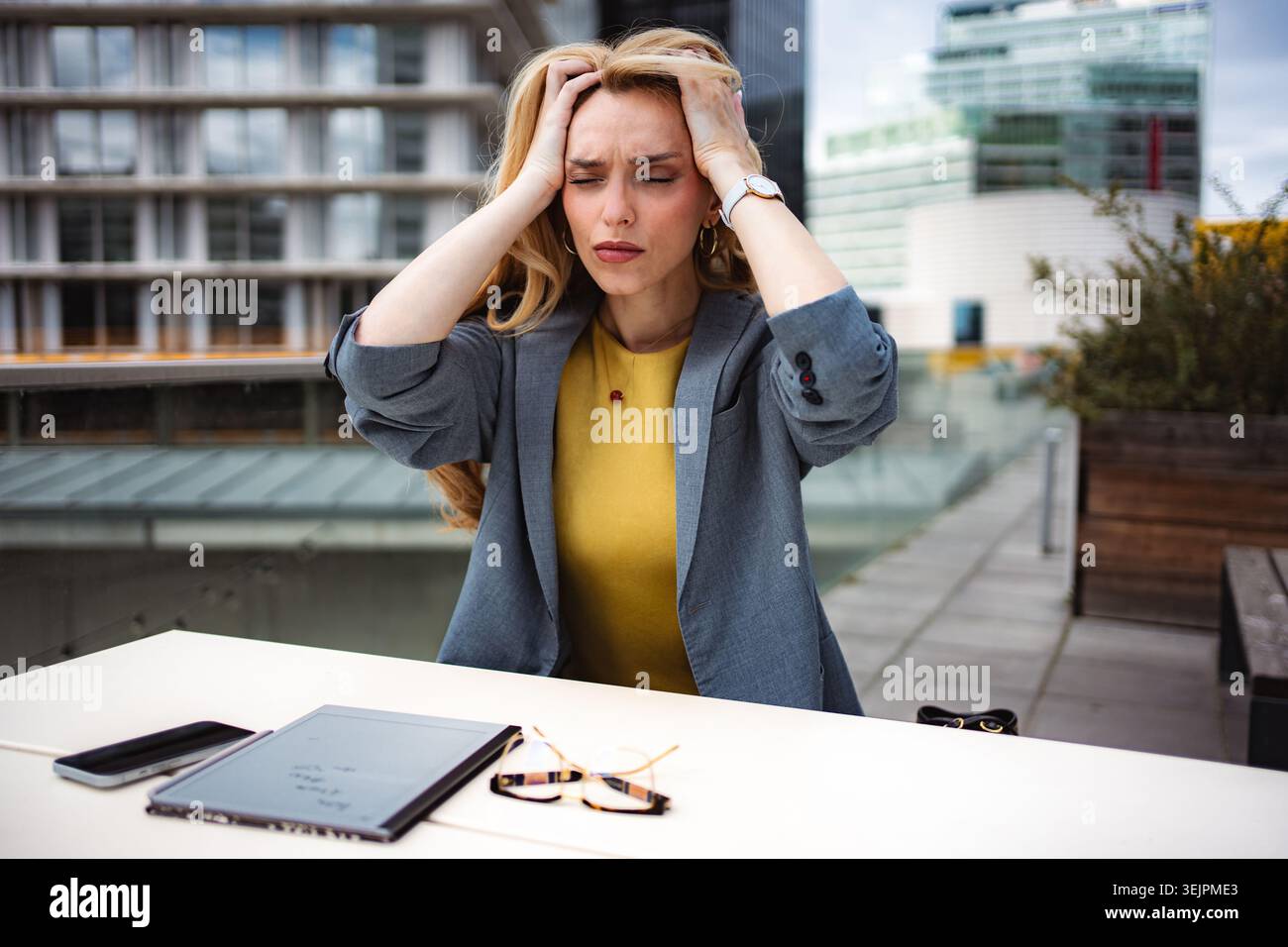 Donna d'affari che soffre di stress, mal di testa e burnout sul tetto urbano Foto Stock