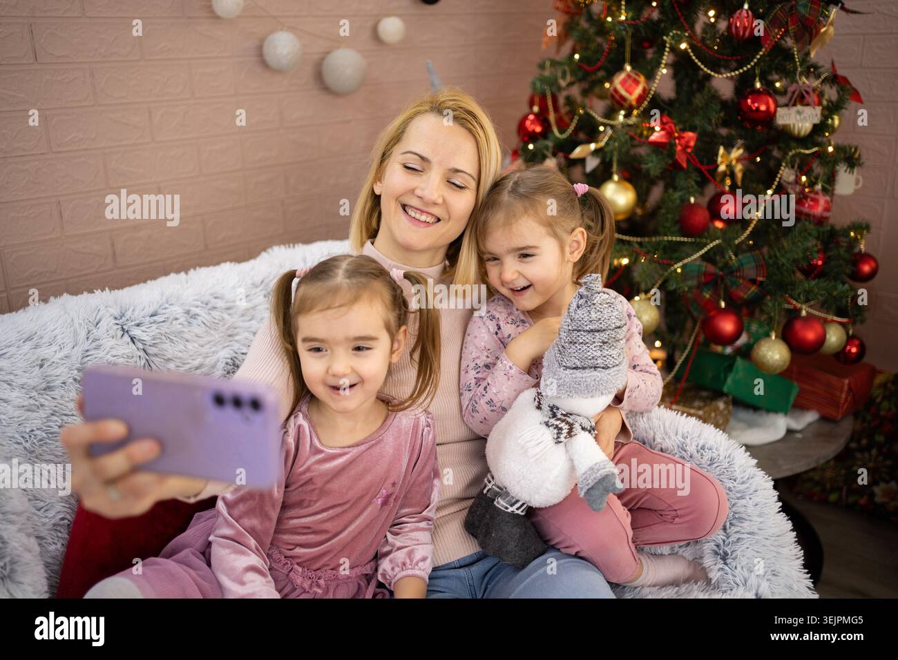 Madre e figlie si fanno selfie sull'albero di natale Foto Stock